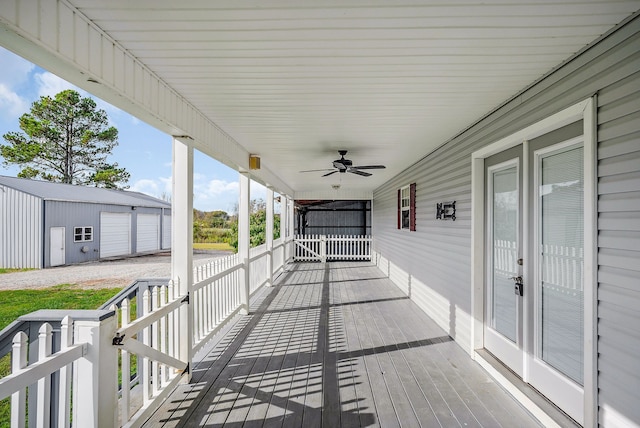 wooden deck with ceiling fan, an outdoor structure, and a garage