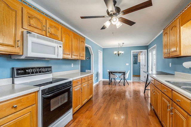 kitchen with ornamental molding, ceiling fan with notable chandelier, white appliances, pendant lighting, and light hardwood / wood-style floors