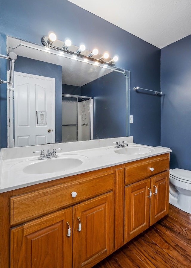 bathroom featuring toilet, vanity, wood-type flooring, and walk in shower