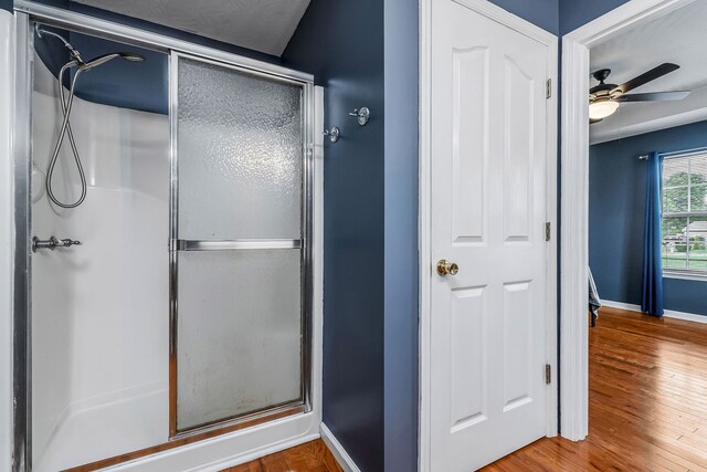 bathroom featuring ceiling fan, a shower with shower door, and hardwood / wood-style flooring