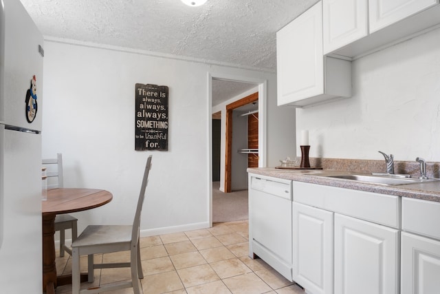 kitchen featuring white dishwasher, sink, white cabinets, light tile patterned floors, and refrigerator