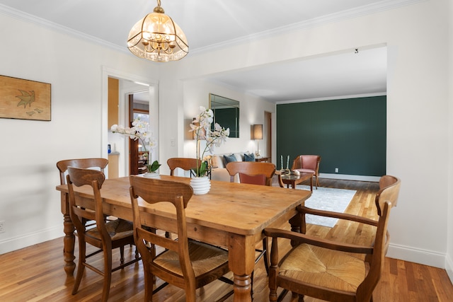 dining space featuring wood-type flooring, crown molding, and a chandelier