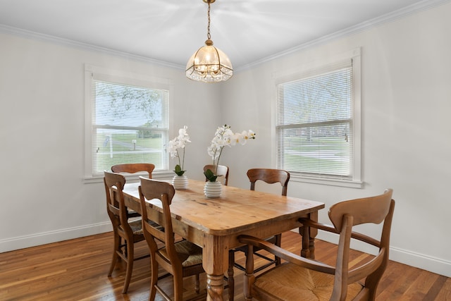 dining area with wood-type flooring, ornamental molding, and a chandelier