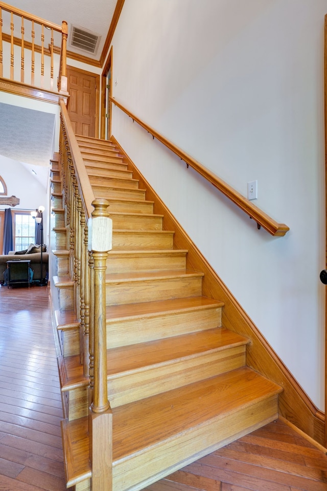 stairway with crown molding and hardwood / wood-style flooring