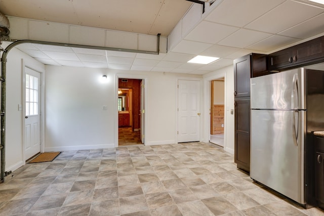 kitchen with stainless steel fridge, dark brown cabinetry, and a paneled ceiling