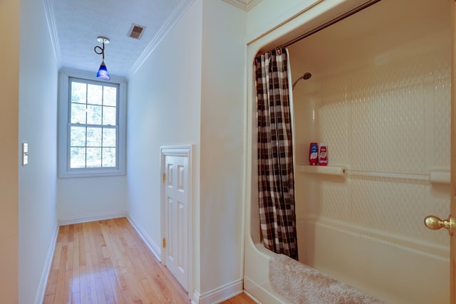 bathroom featuring hardwood / wood-style floors, shower / bath combo, and ornamental molding