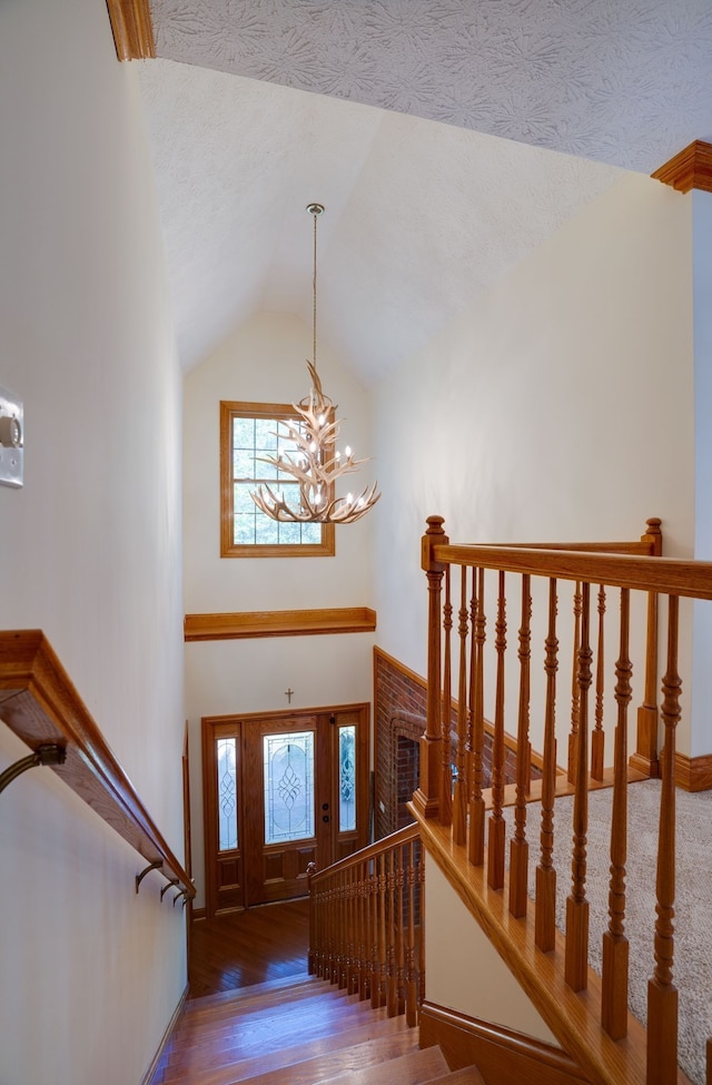 foyer featuring a textured ceiling, wood-type flooring, vaulted ceiling, and an inviting chandelier