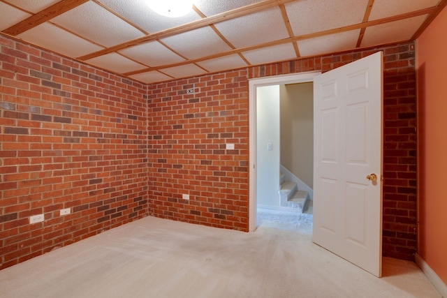 spare room featuring light carpet and brick wall