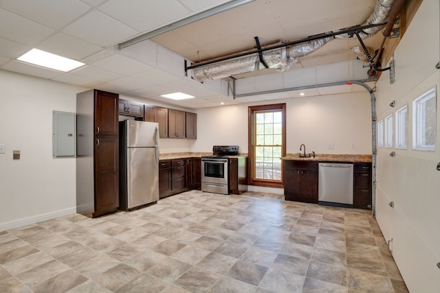 kitchen with a paneled ceiling, dark brown cabinets, stainless steel appliances, sink, and electric panel