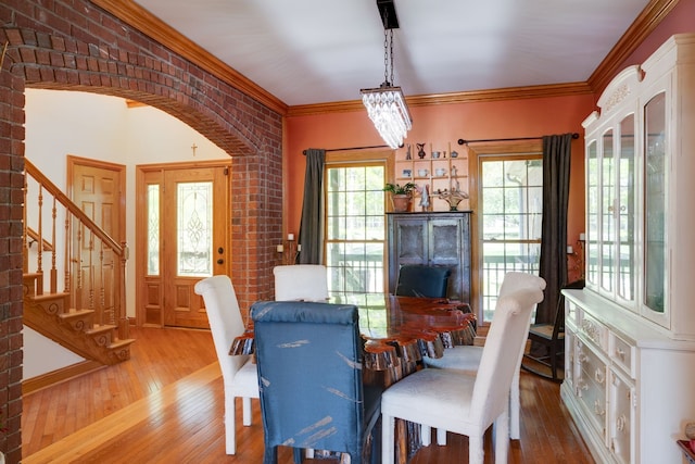 dining room featuring crown molding, brick wall, and light hardwood / wood-style flooring