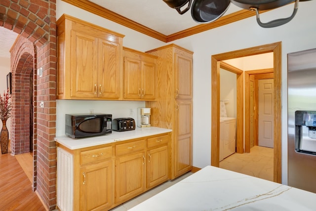 kitchen featuring stainless steel refrigerator with ice dispenser, light wood-type flooring, washer / dryer, light brown cabinetry, and ornamental molding