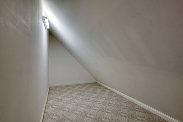 unfurnished room featuring light colored carpet and vaulted ceiling