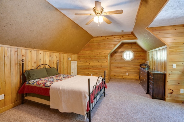 bedroom with ceiling fan, wood walls, a textured ceiling, and light carpet