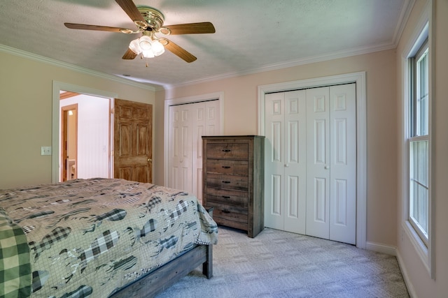 carpeted bedroom featuring multiple windows, two closets, ceiling fan, and crown molding