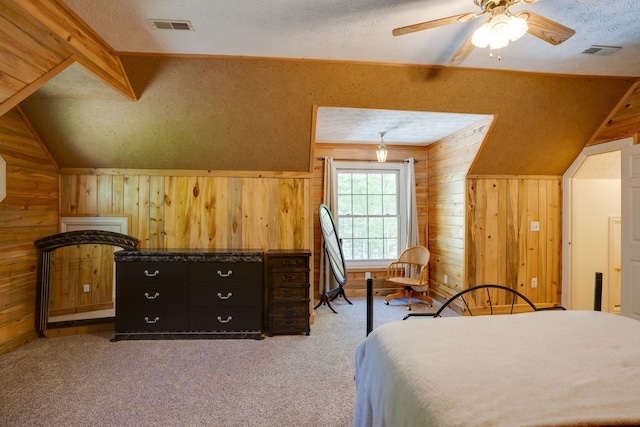 bedroom featuring ceiling fan, wood walls, light colored carpet, a textured ceiling, and vaulted ceiling