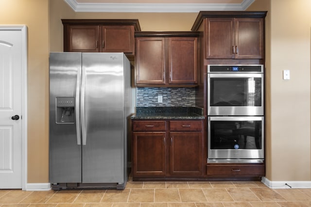 kitchen featuring dark stone counters, crown molding, light tile patterned floors, appliances with stainless steel finishes, and tasteful backsplash