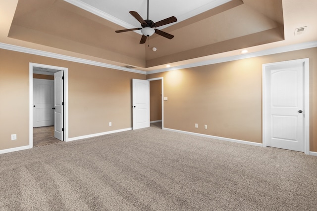 unfurnished bedroom with carpet flooring, a raised ceiling, and ornamental molding