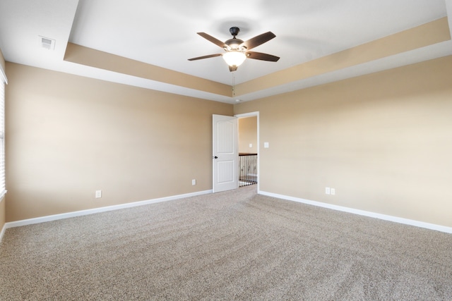 spare room with carpet, ceiling fan, and a raised ceiling