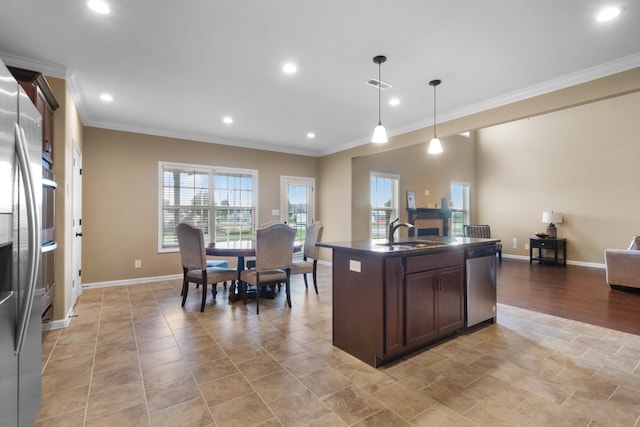 kitchen with ornamental molding, decorative light fixtures, stainless steel dishwasher, and a center island with sink