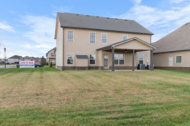 rear view of house with a yard, ceiling fan, and central air condition unit