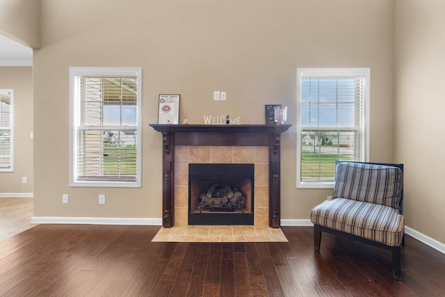 sitting room with a tiled fireplace and hardwood / wood-style flooring