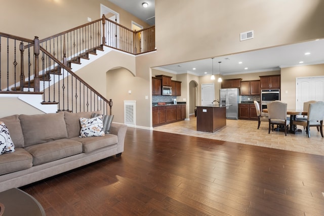 living room with crown molding, light hardwood / wood-style flooring, and a towering ceiling