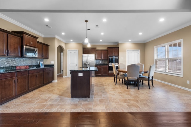 kitchen with decorative light fixtures, light hardwood / wood-style flooring, an island with sink, and stainless steel appliances