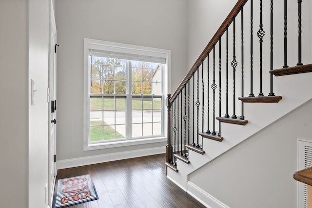 stairway with a healthy amount of sunlight and hardwood / wood-style flooring