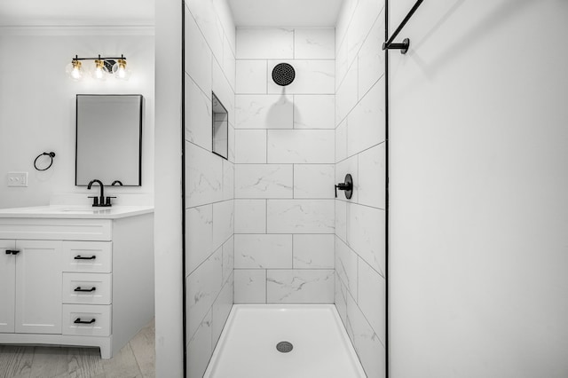 bathroom with vanity, tiled shower, and crown molding