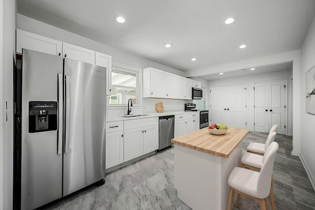 kitchen with white cabinetry, sink, a breakfast bar area, and appliances with stainless steel finishes