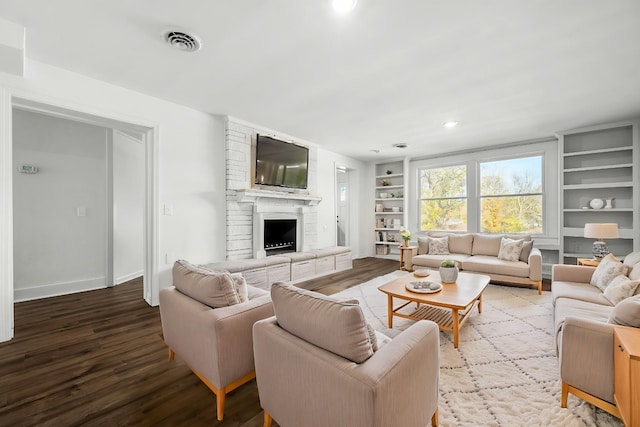 living room featuring hardwood / wood-style flooring, a fireplace, and built in shelves