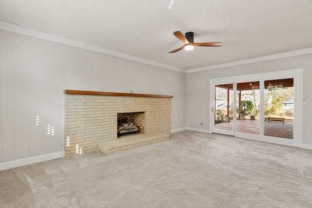 unfurnished living room featuring light carpet, a brick fireplace, ceiling fan, ornamental molding, and a textured ceiling