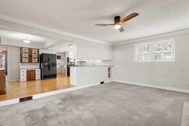 unfurnished living room with ceiling fan, crown molding, light carpet, and a textured ceiling