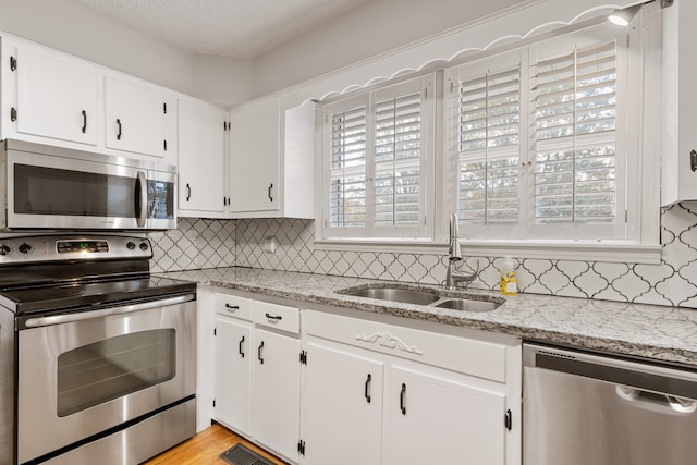 kitchen featuring light stone countertops, white cabinetry, sink, and appliances with stainless steel finishes