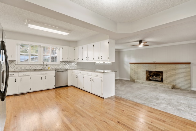 kitchen featuring a brick fireplace, a textured ceiling, stainless steel appliances, ceiling fan, and white cabinets