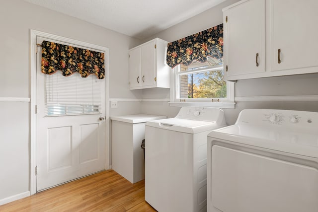 clothes washing area with washer and dryer, cabinets, a textured ceiling, and light wood-type flooring