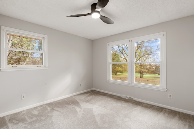 spare room featuring a textured ceiling, light colored carpet, and ceiling fan