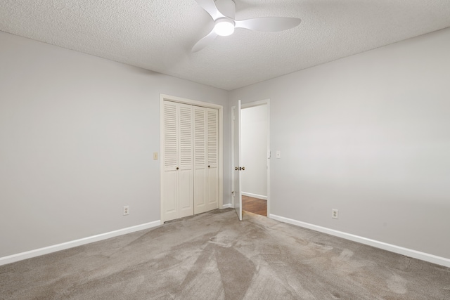 unfurnished bedroom with ceiling fan, a closet, light carpet, and a textured ceiling