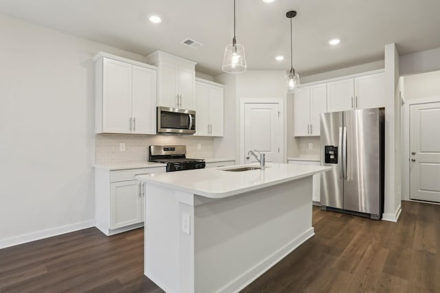 kitchen with appliances with stainless steel finishes, hanging light fixtures, an island with sink, sink, and white cabinetry