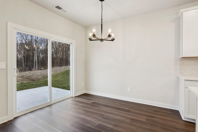 unfurnished dining area with a chandelier and dark hardwood / wood-style floors