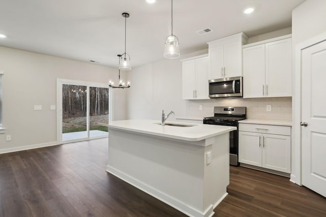 kitchen featuring sink, white cabinetry, stainless steel appliances, hanging light fixtures, and an island with sink