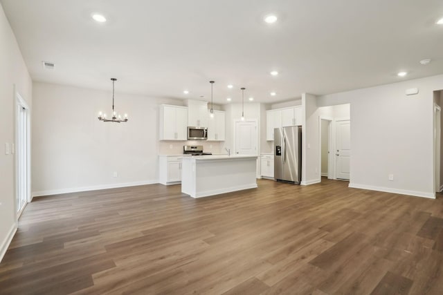 unfurnished living room featuring sink, an inviting chandelier, and wood-type flooring