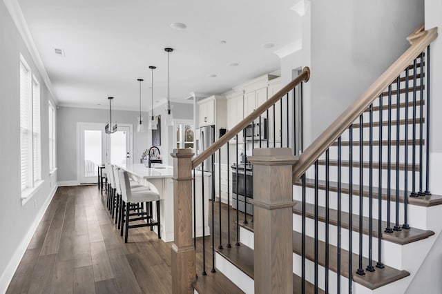 stairs with crown molding, wood-type flooring, and sink