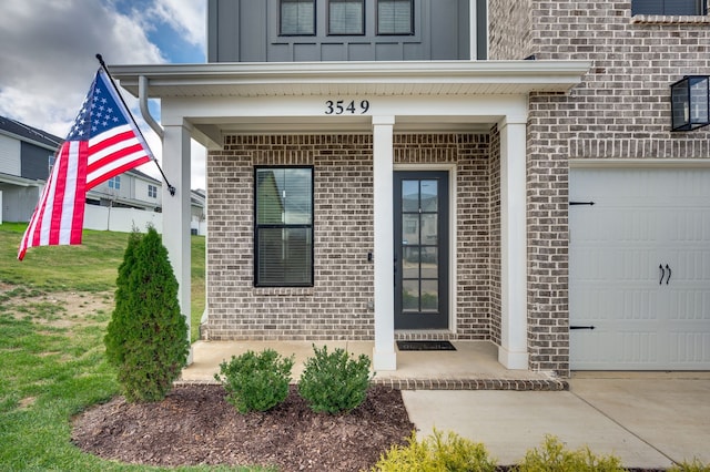 view of exterior entry featuring a porch, a garage, and a yard