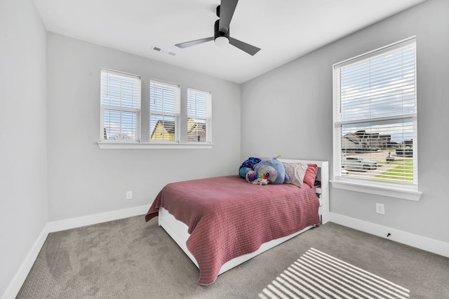 carpeted bedroom featuring multiple windows and ceiling fan