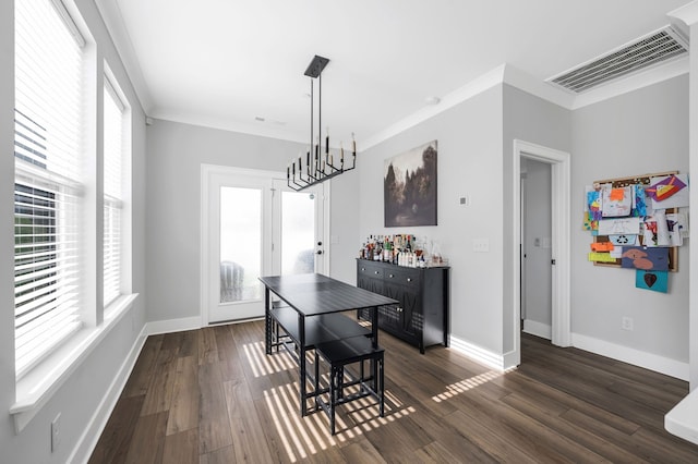 dining room with a notable chandelier, crown molding, dark wood-type flooring, and bar