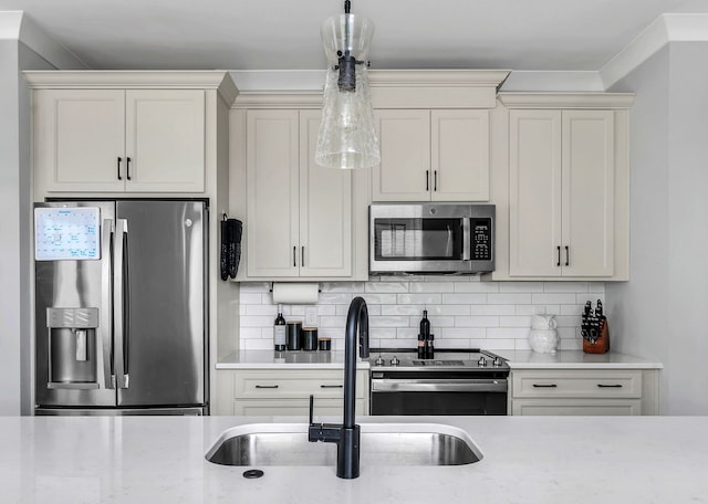 kitchen featuring light stone countertops, appliances with stainless steel finishes, tasteful backsplash, sink, and hanging light fixtures