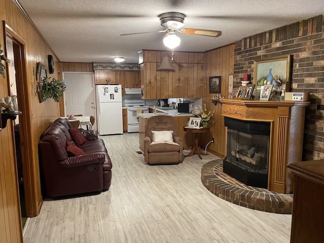 living room featuring a fireplace, a textured ceiling, light hardwood / wood-style floors, and wood walls