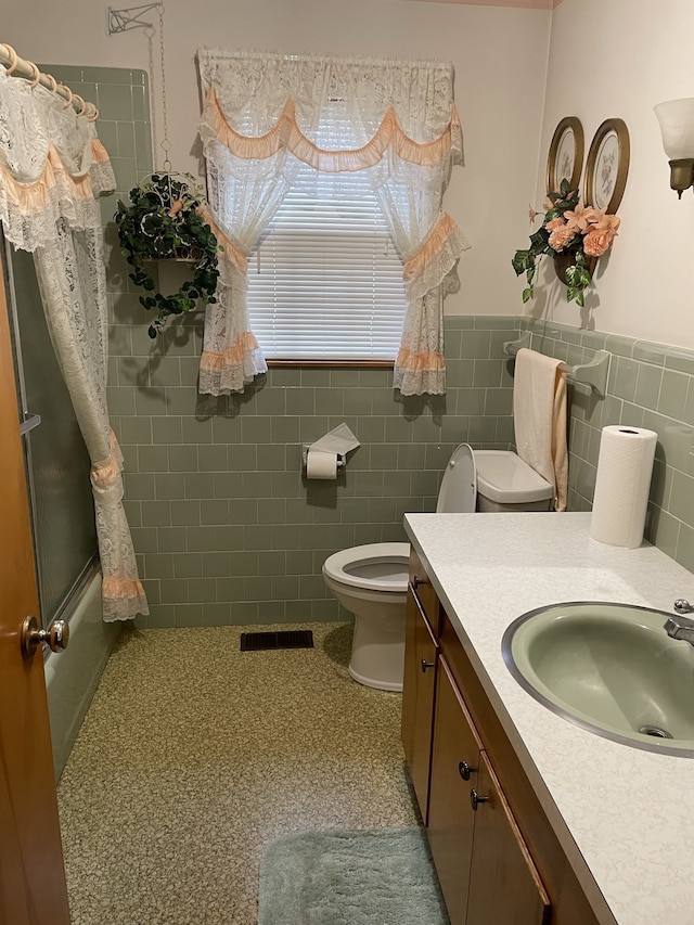 full bathroom featuring shower / tub combo with curtain, vanity, tile walls, and toilet