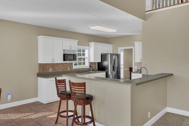 kitchen featuring white cabinets, kitchen peninsula, stainless steel refrigerator with ice dispenser, and built in microwave